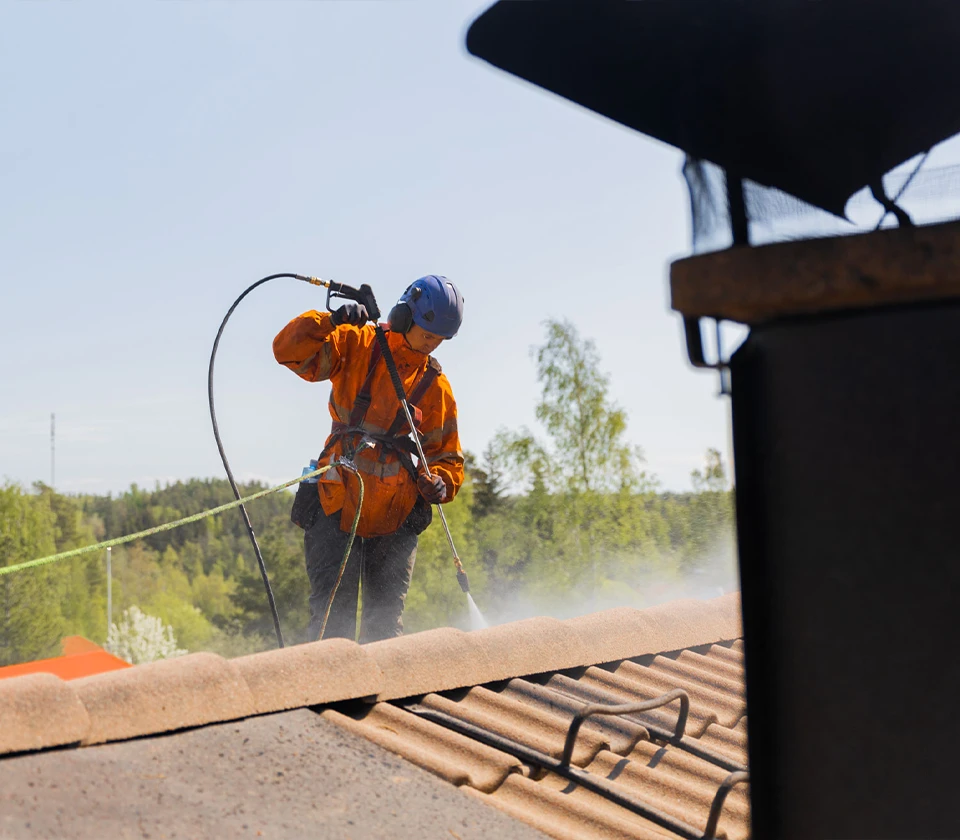 Väriympyrän huoltomies tekemässä tiilikaton pesua katolla.